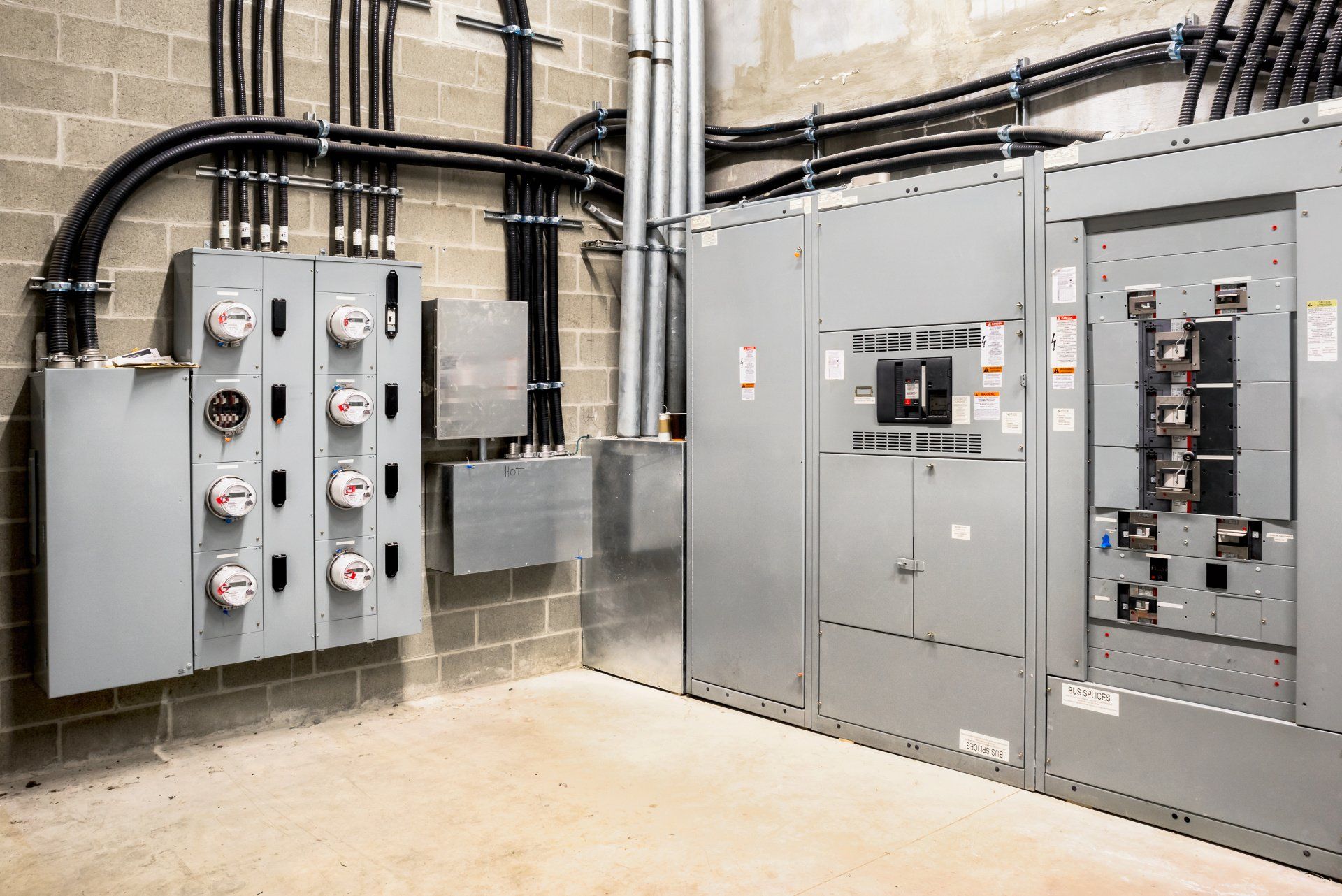 An electrical room in a commercial building, featuring multiple smart meters, the main power breaker, and meter stacks.