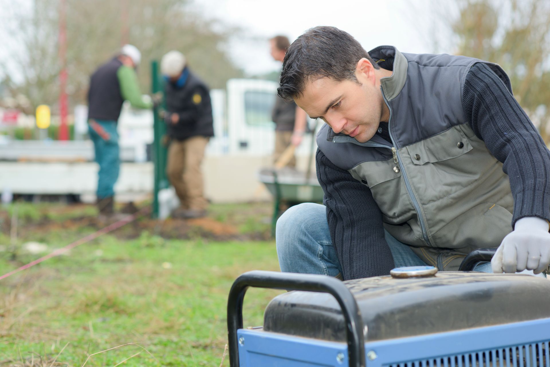 A builder operating an air compressor to power construction tools.