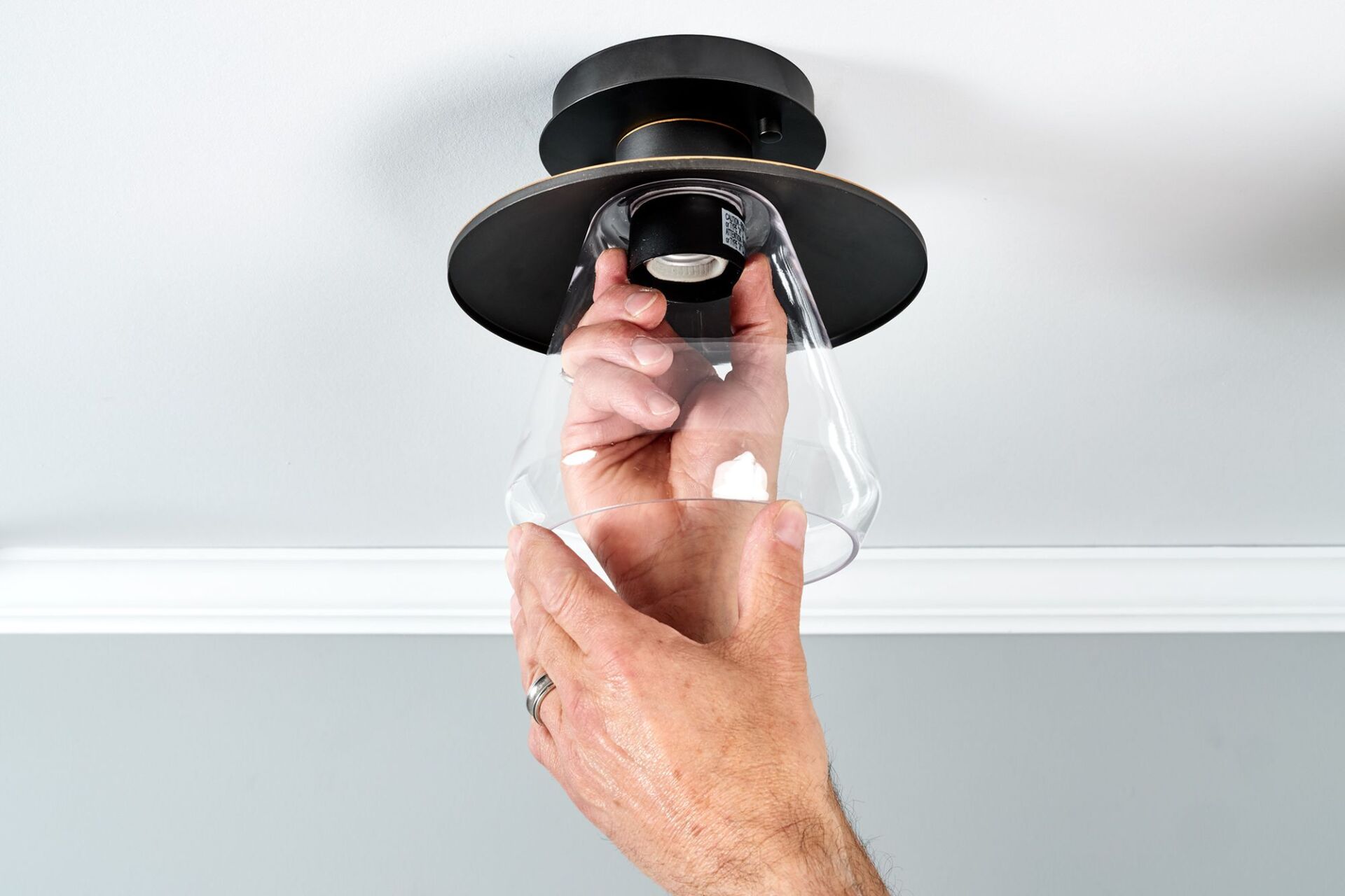 A person installing a ceiling light fixture in a room.