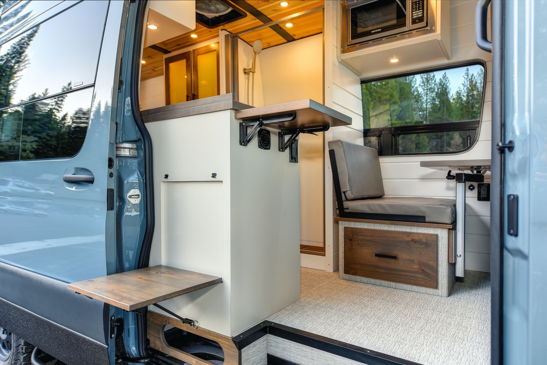 Interior of a camper van with cozy seating and kitchenette.