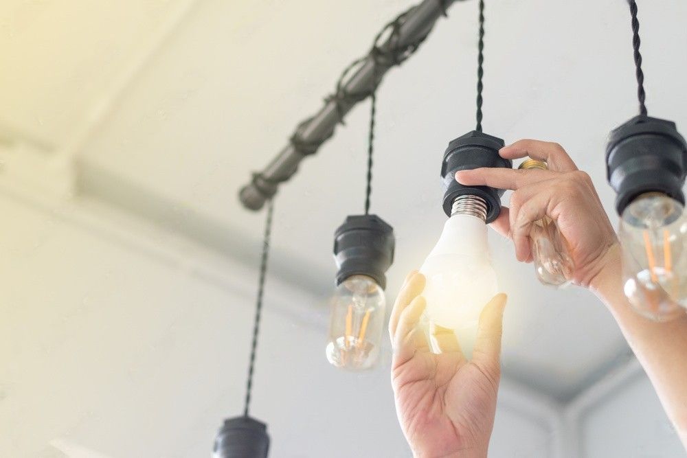 A man replacing compact-fluorescent (CFL) bulbs with energy-efficient LED light bulbs.