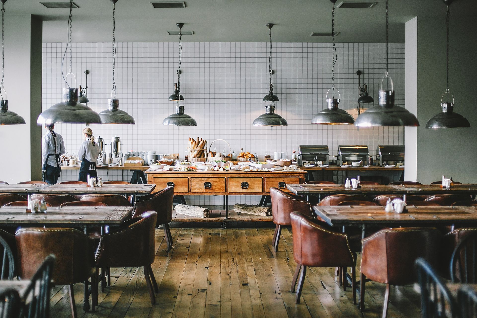 Black stainless pendant lights hanging above tables in a stylish cafeteria.