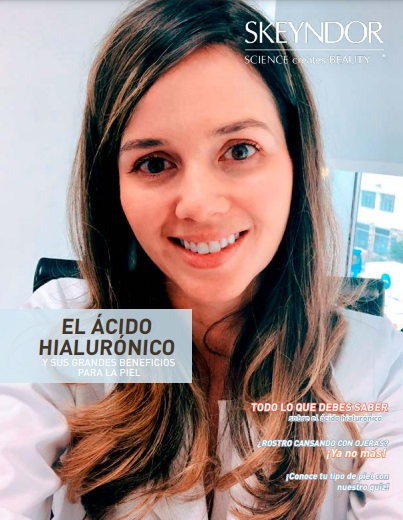 Una mujer con una bata blanca de laboratorio sonríe frente a un cartel que dice el ácido hialurónico.