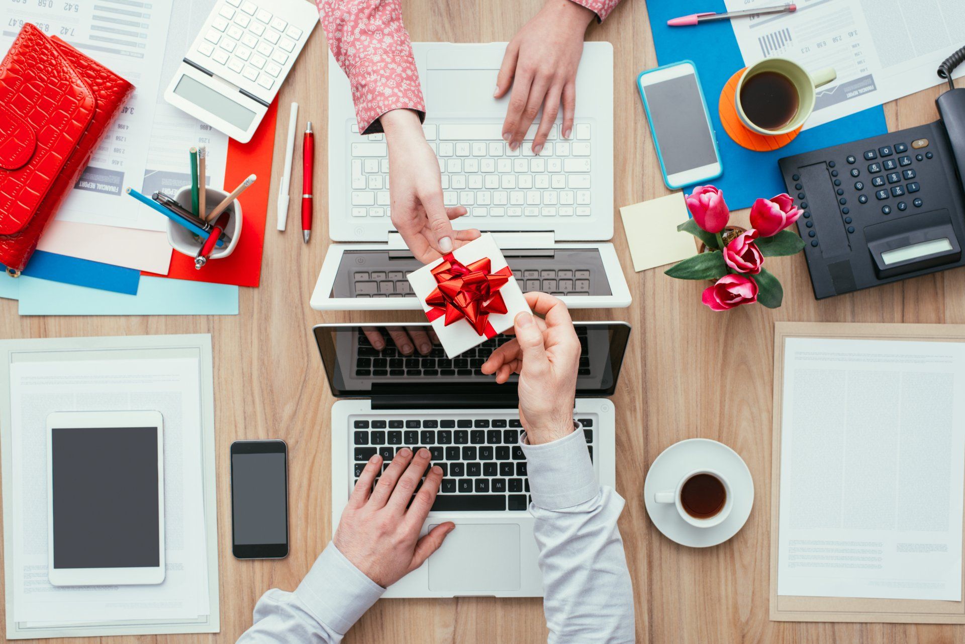 Woman receiving a beautiful gift from her male colleague while working in the office;