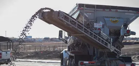 A truck is being loaded with gravel from a conveyor belt.