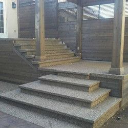 A set of stairs leading up to a porch with a wooden fence in the background.