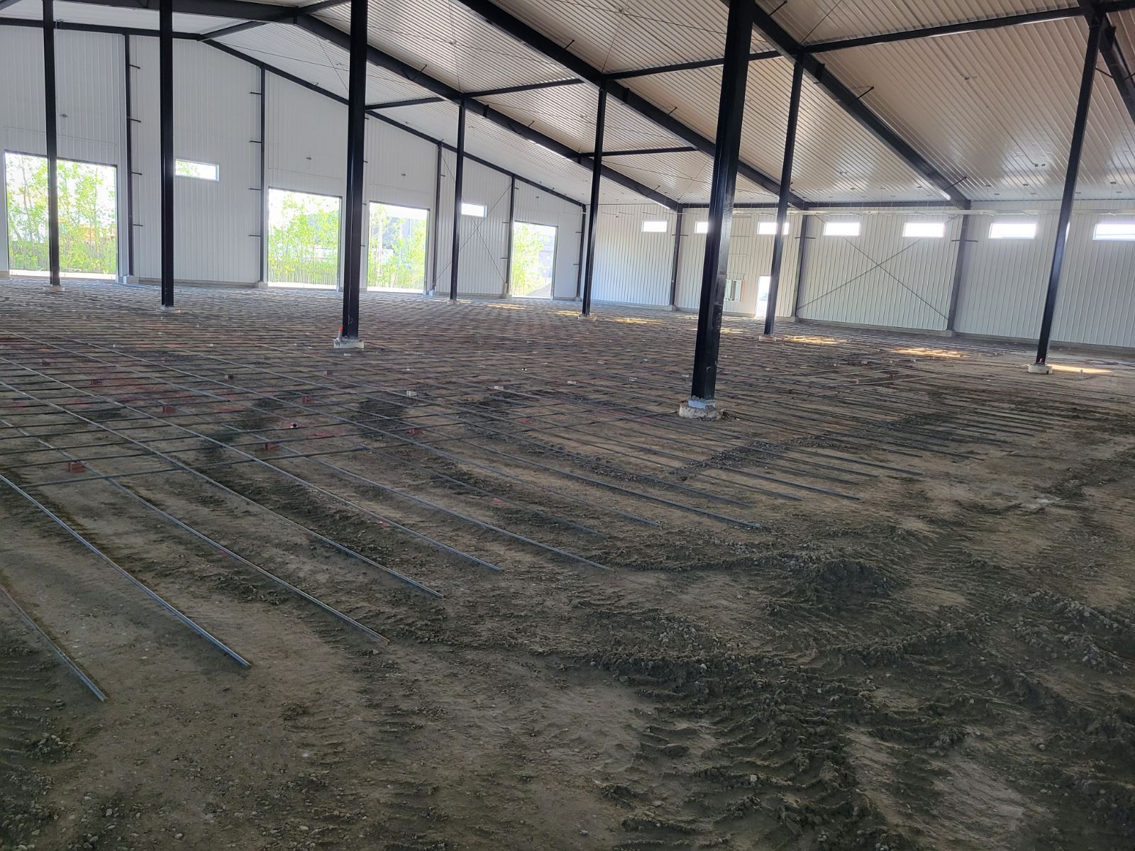 A large empty building with a lot of dirt on the floor.