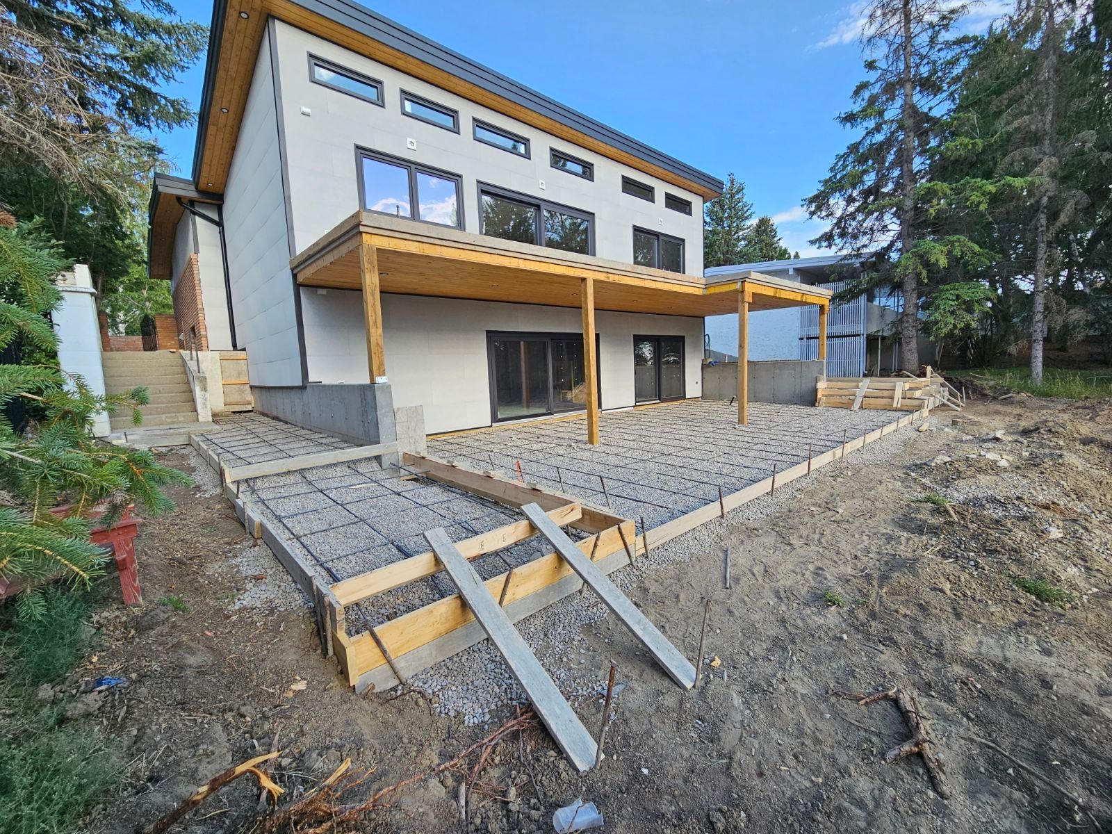 A house is being built on a hill with a concrete patio in front of it.