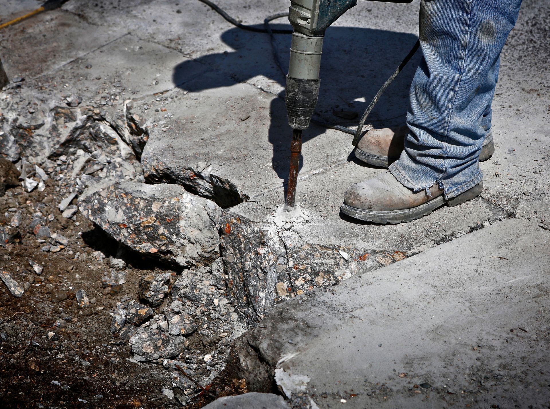 A person is using a hammer to break concrete.