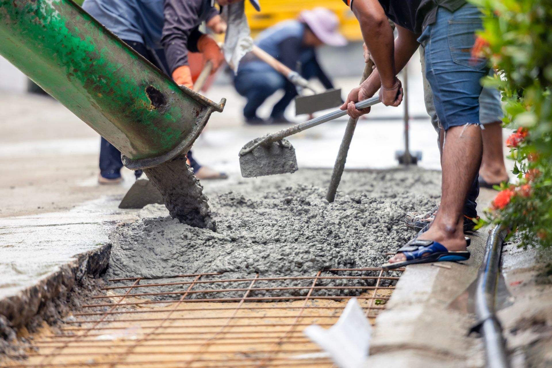 A group of construction workers are pouring concrete on a sidewalk.