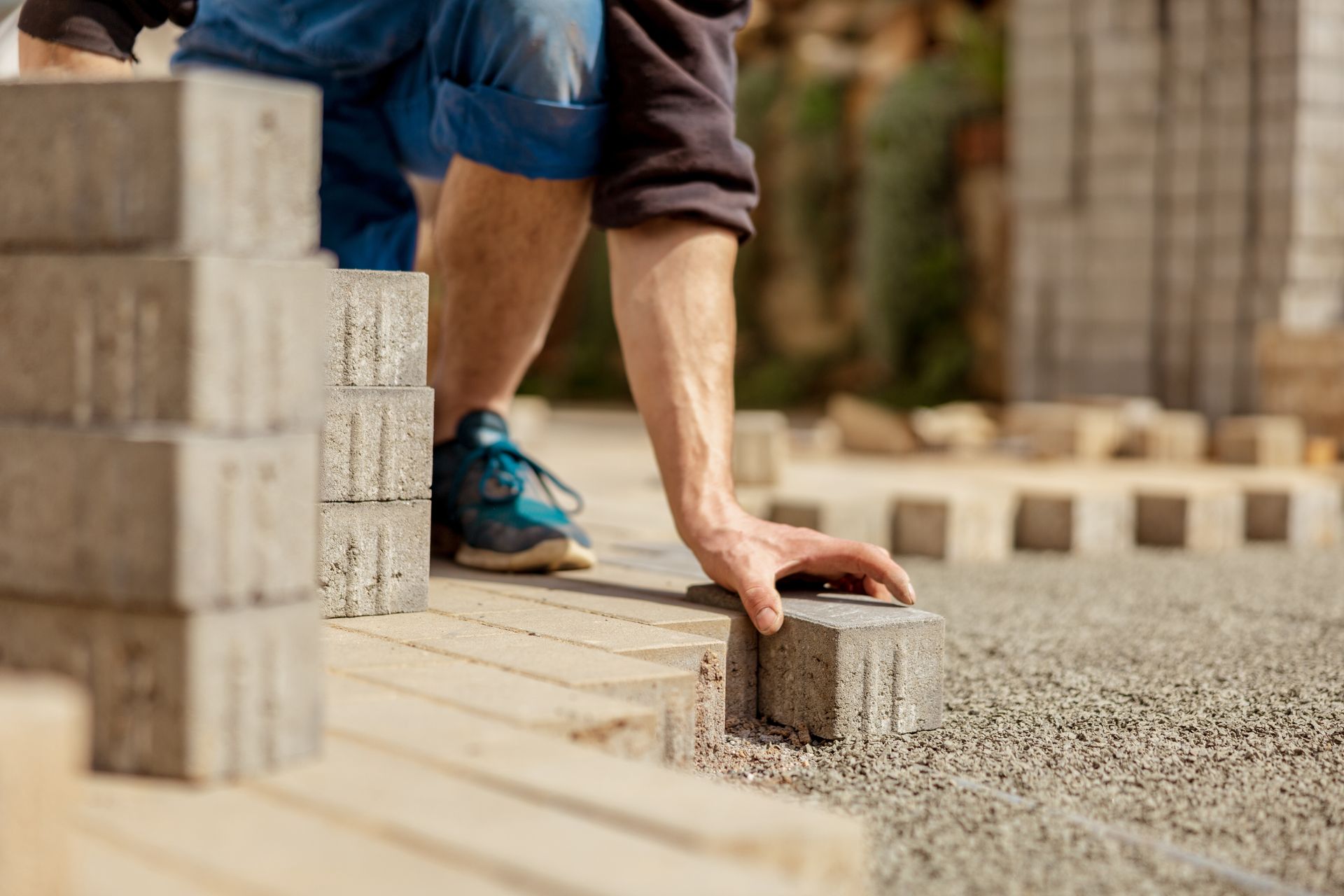 A man is laying bricks on a sidewalk.