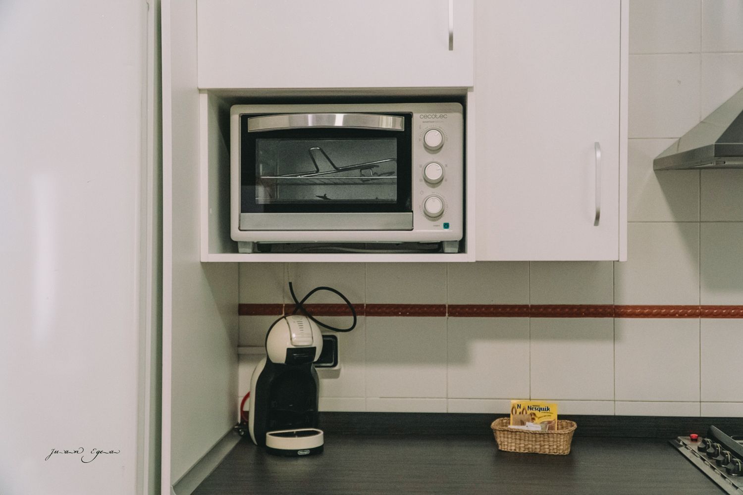 Encimera de cocina con máquina de café expreso, horno pequeño y cesta.