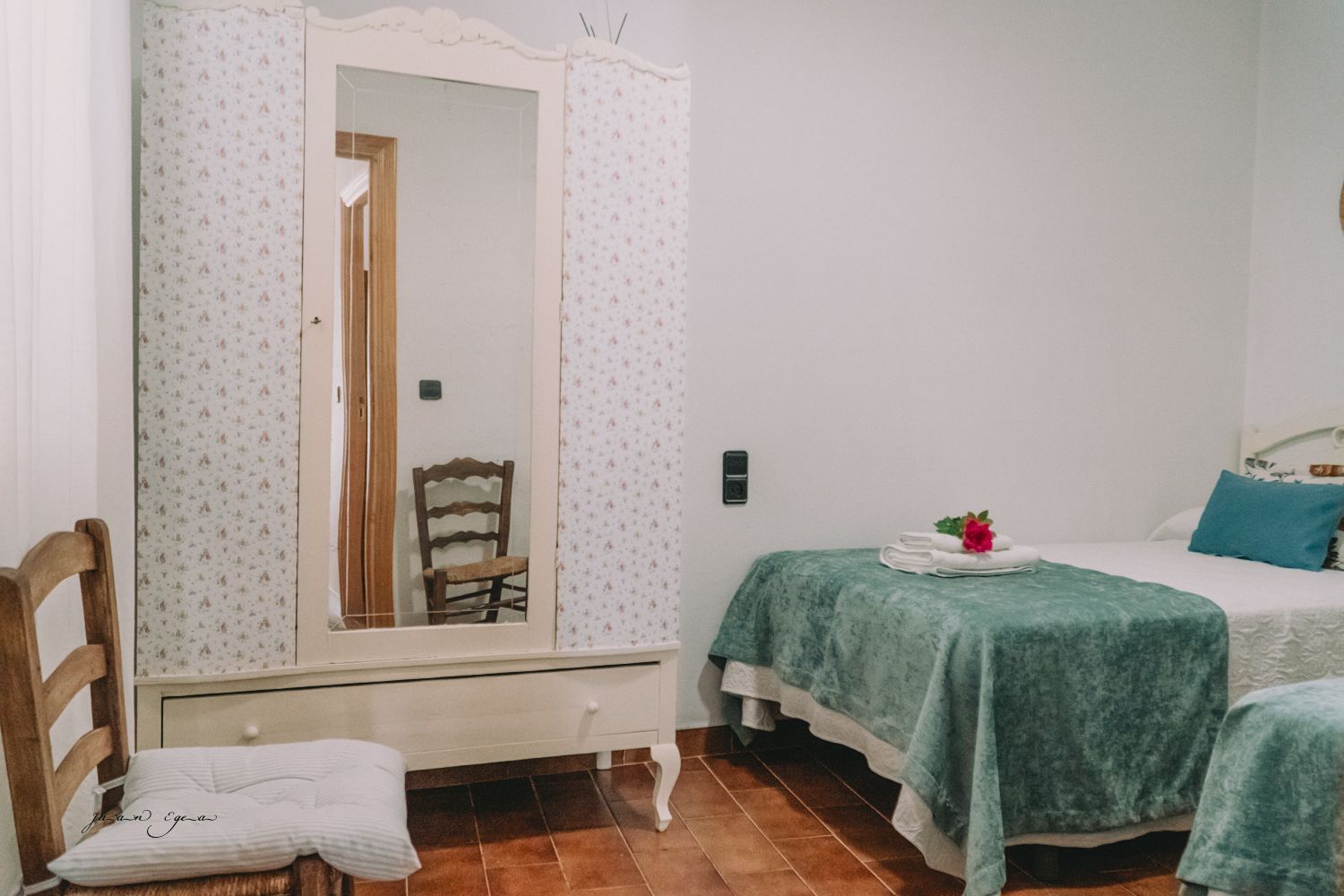 Dormitorio con dos camas individuales y un armario alto con espejo.