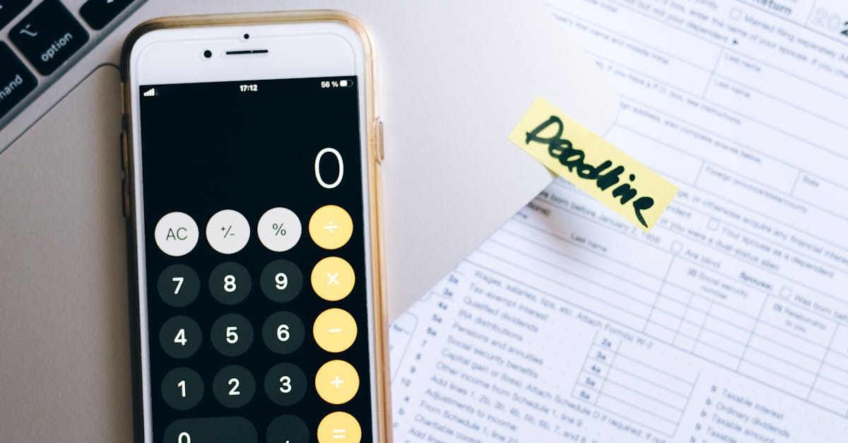 A cell phone is sitting on a table next to a calculator and a sticky note that says deadline.
