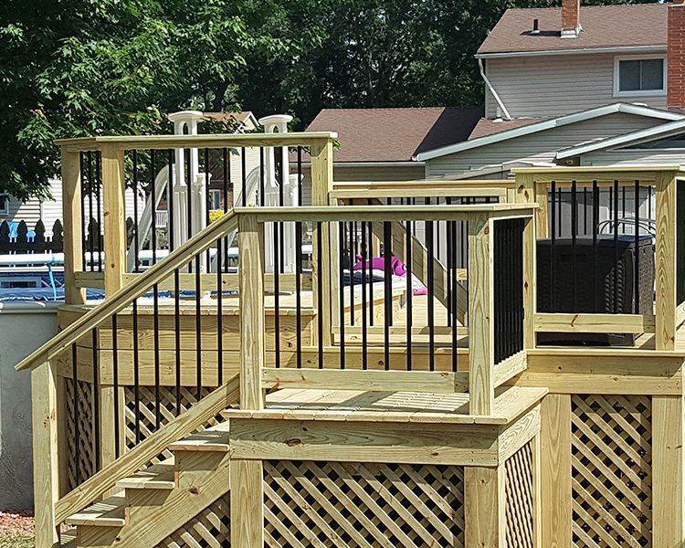 Newly built wooden deck with black metal balusters and lattice skirting around an above-ground swimming pool.