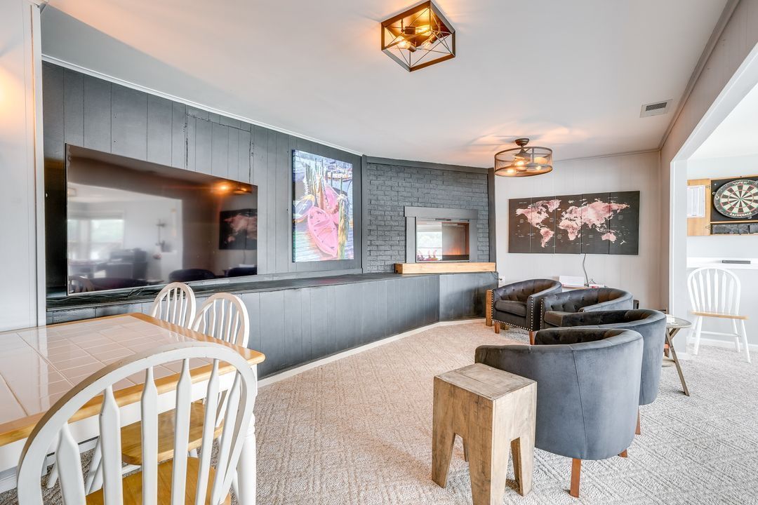Living room with gray paneling, large TV, chairs, fireplace, and world map decor.