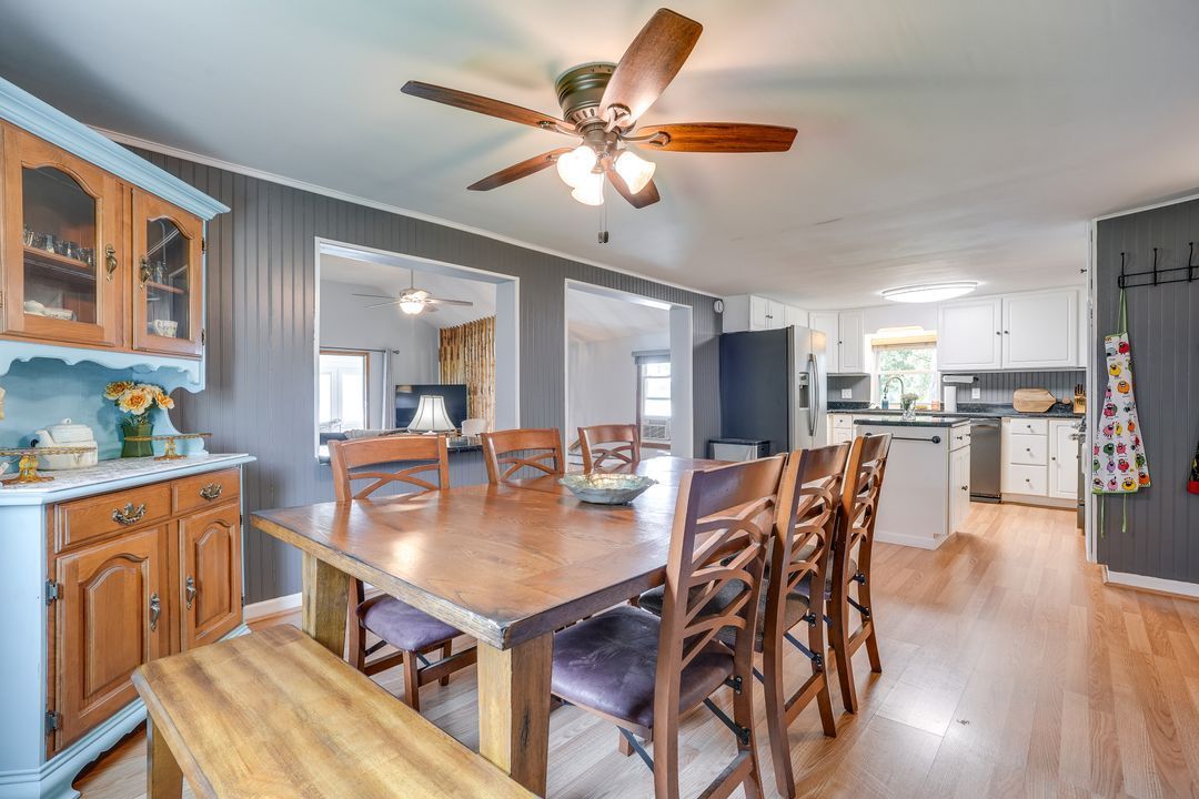 Dining room with wooden table and chairs, buffet, and open view to the kitchen.