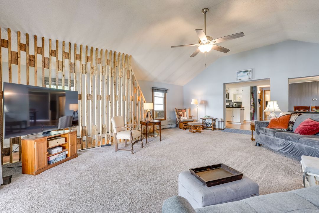 Living room with wooden pallet wall, TV, gray couch, and light carpet.