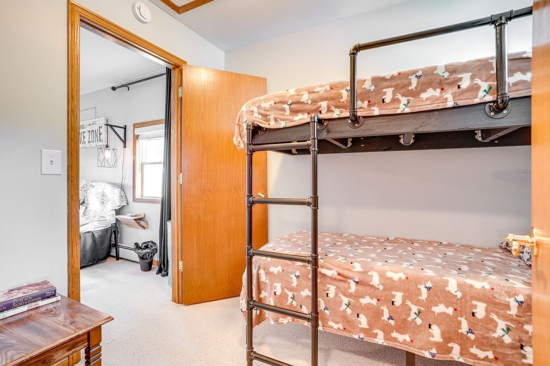 Bunk beds in a room, with a door leading to a bathroom. The beds have dog-print blankets.