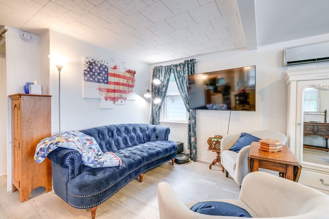 Living room with a blue velvet sofa, American flag art, and a mounted TV.