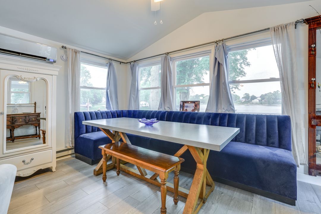 Blue upholstered booth with a wooden table and bench in front of a window. A white cabinet is to the left.