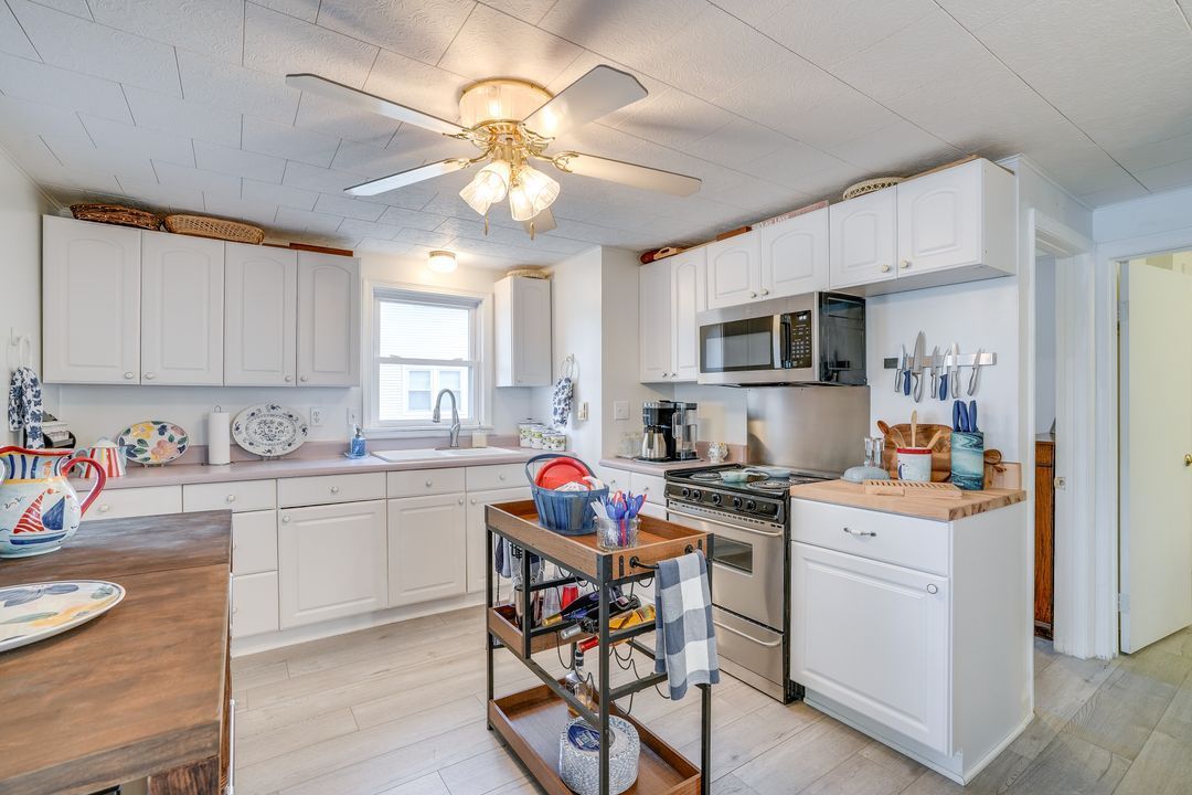 White kitchen with cabinets, stainless steel appliances, and a wooden cart.