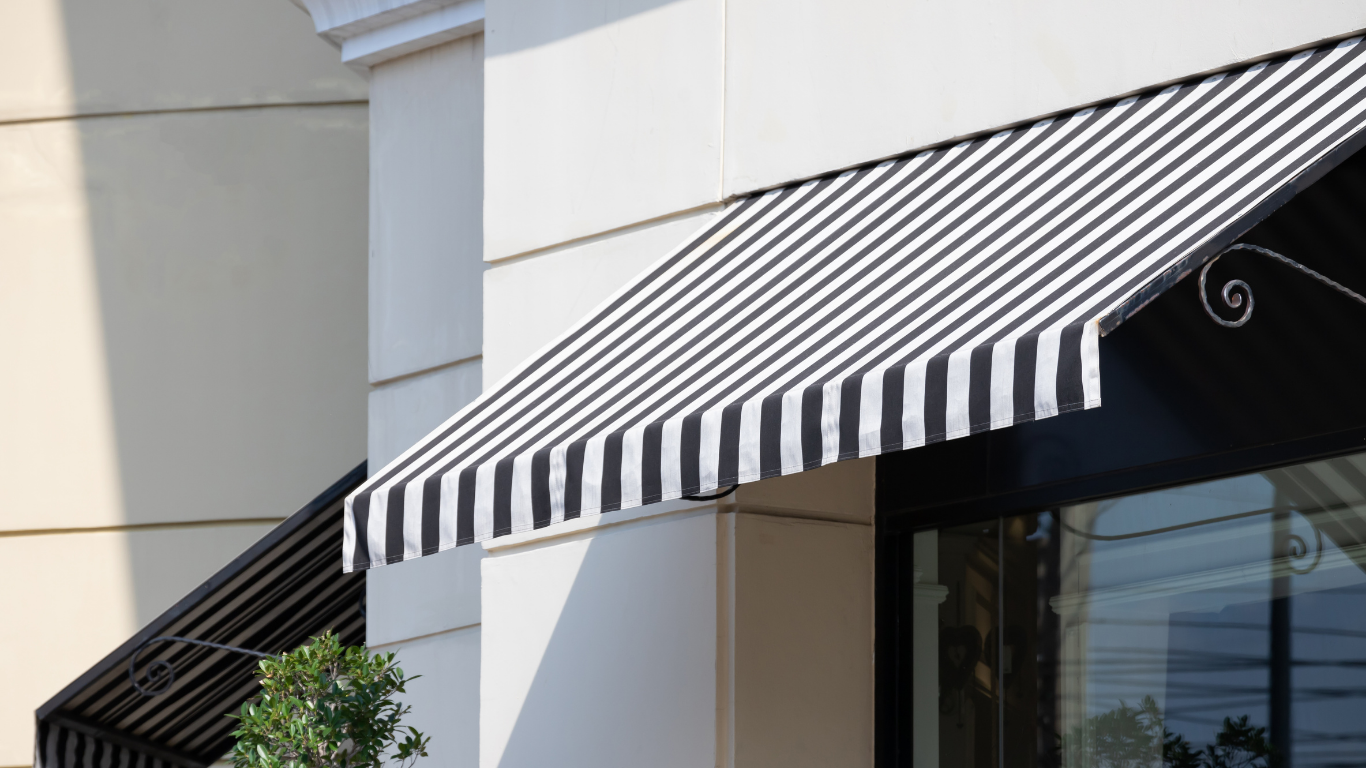 Black and white striped awning over a storefront window on a white building.