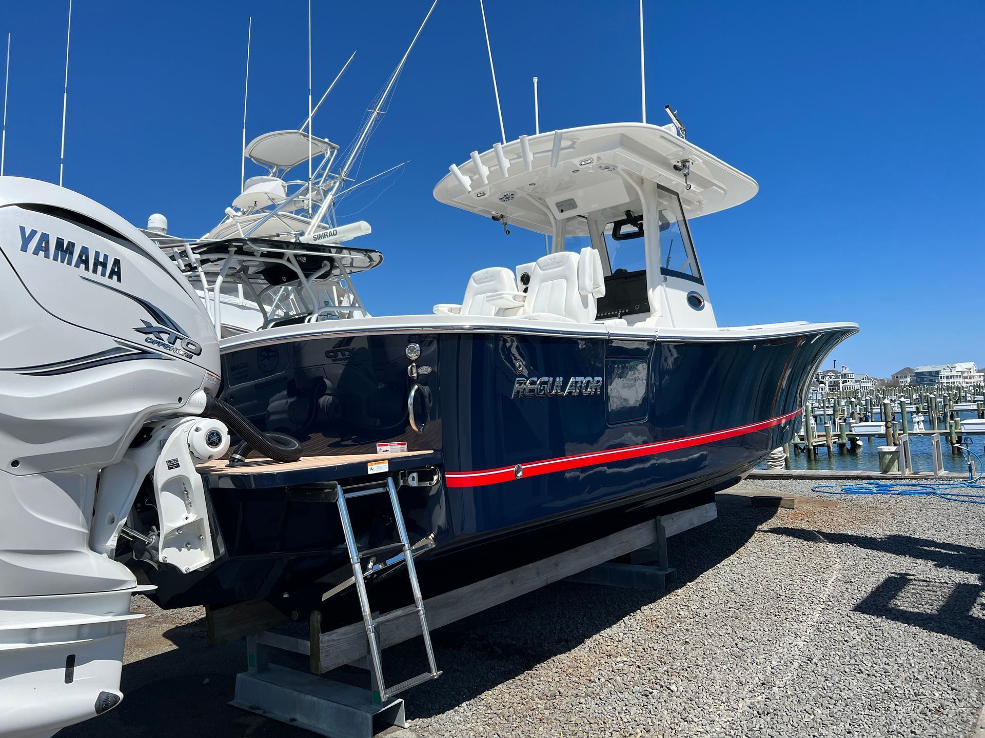Blue and white sport fishing boat docked outdoors under a clear sky. A Yamaha engine is visible.