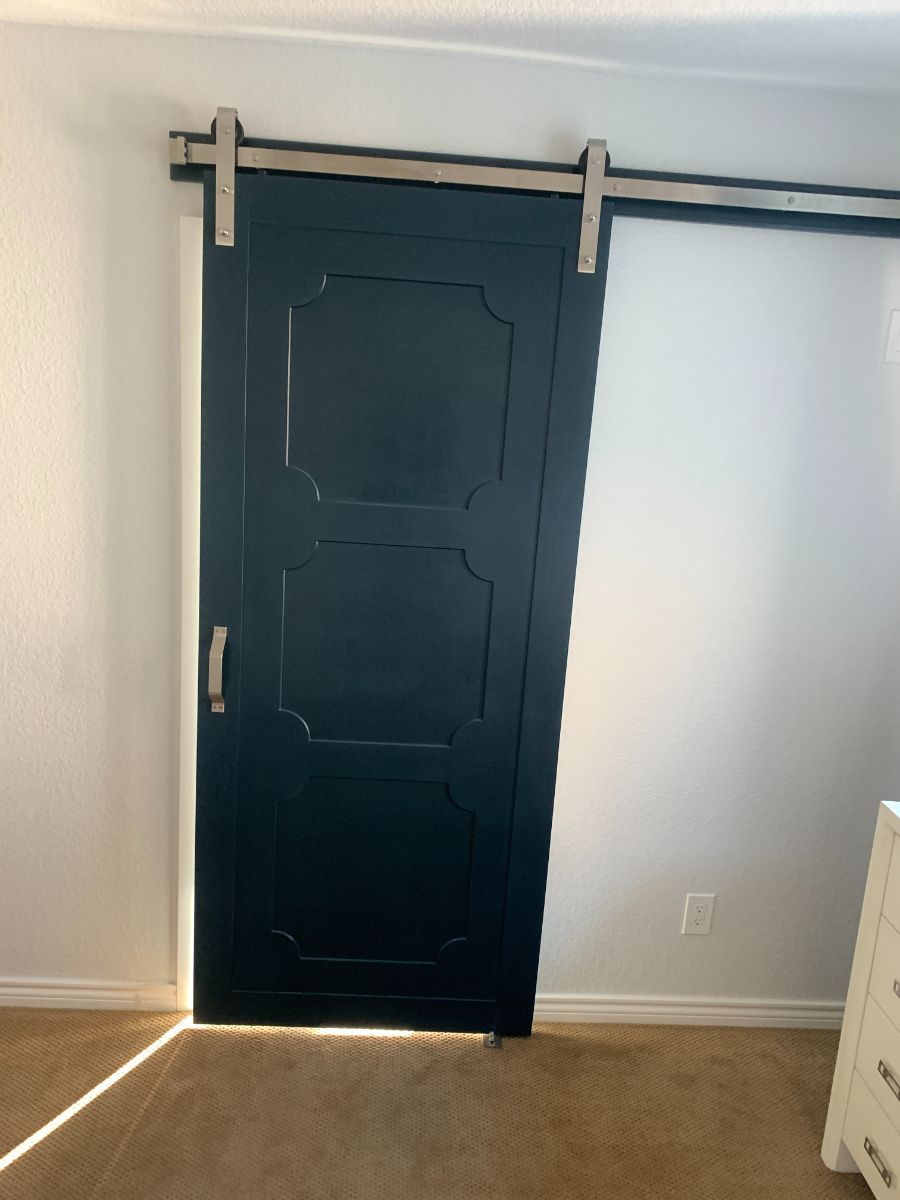 a bedroom with a sliding barn door and a white dresser