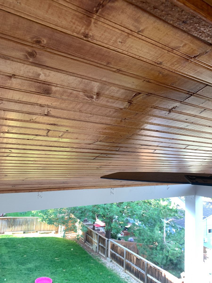 a wooden ceiling with a view of a backyard and a fence .