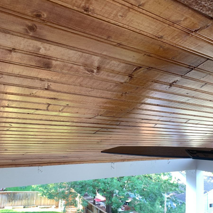a wooden ceiling with a ceiling fan on a porch .