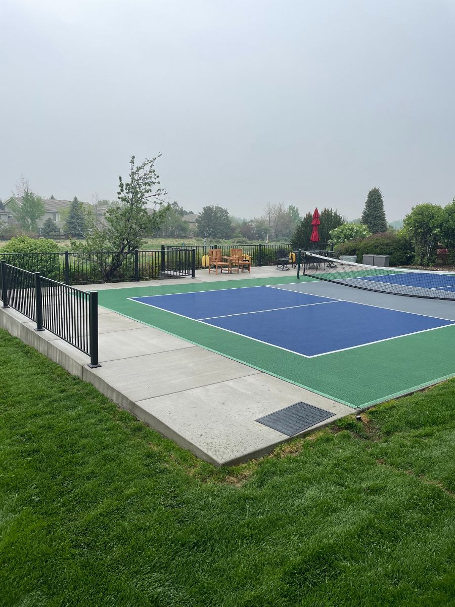 a blue and green tennis court with a fence in the background .