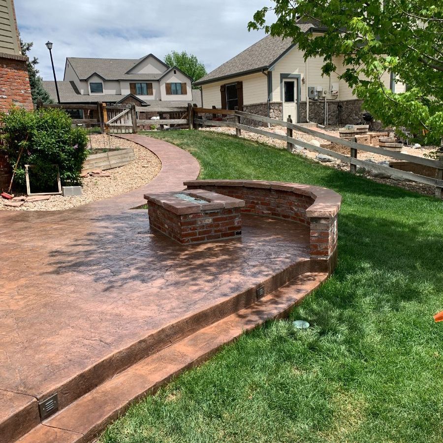 a brick walkway leading to a house with a fence in the background