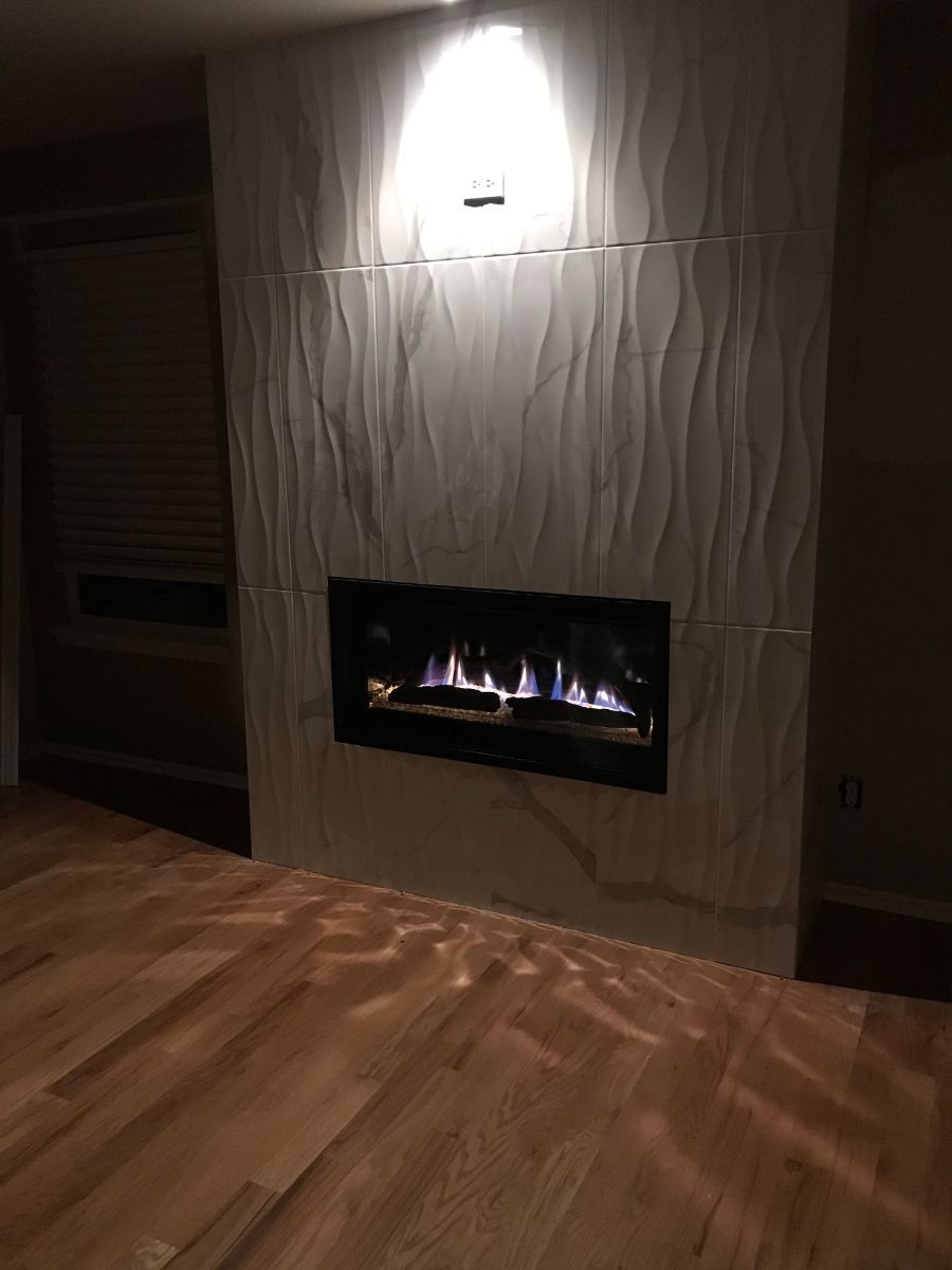 a fireplace in a dark room with a wooden floor