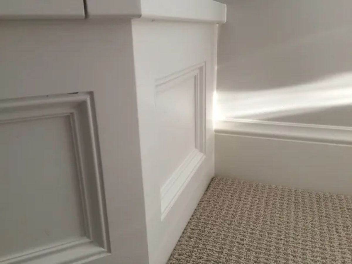 a white cabinet is sitting on a carpeted floor next to a white wall .