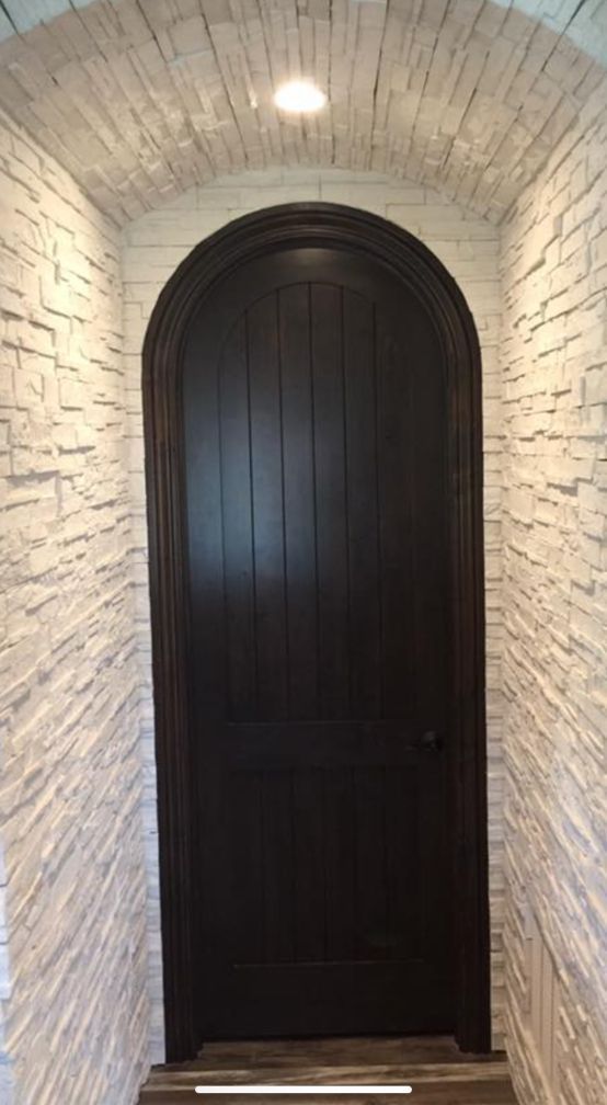 a black door is in a hallway with a white brick wall .