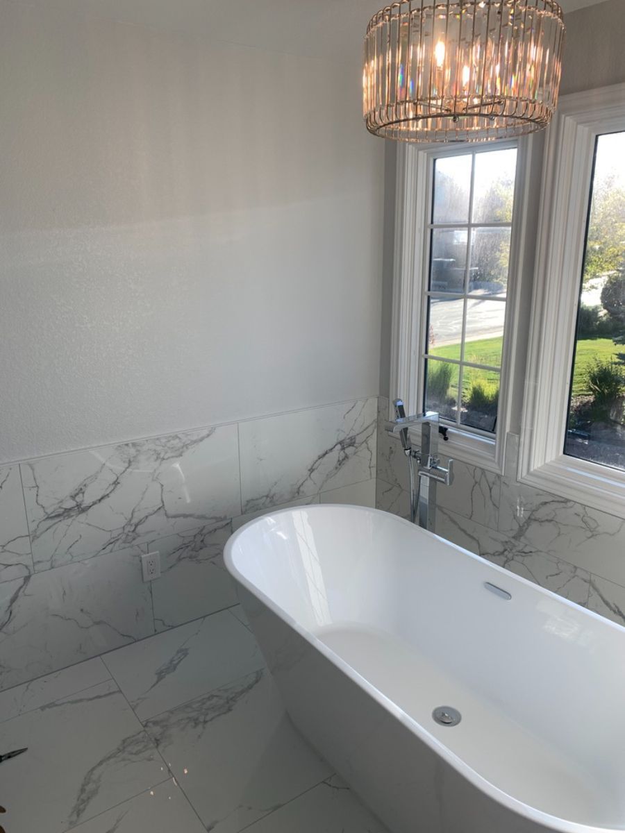 a bathroom with a bathtub and a chandelier hanging from the ceiling .