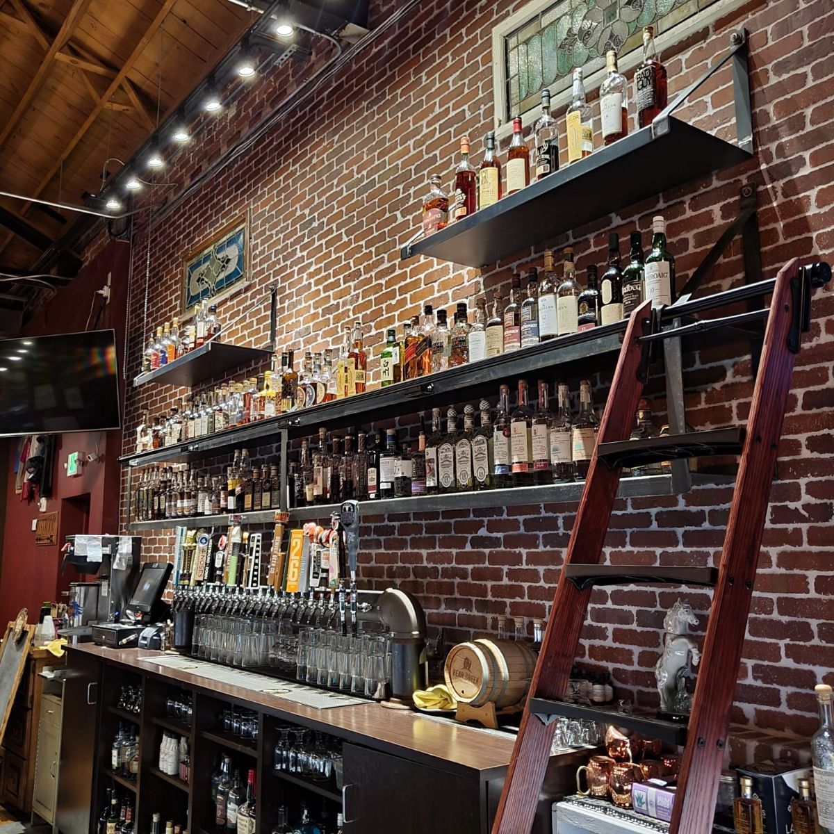 a bar with a ladder and lots of bottles on shelves