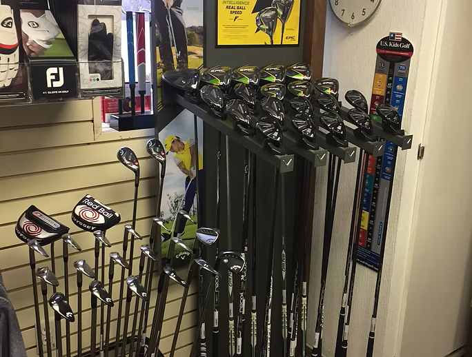 Golf clubs displayed for sale in a store. Some clubs are in a rack, others are in a stand.