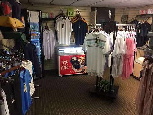 Clothing store interior with golf shirts, racks of apparel, and an ice cream freezer.