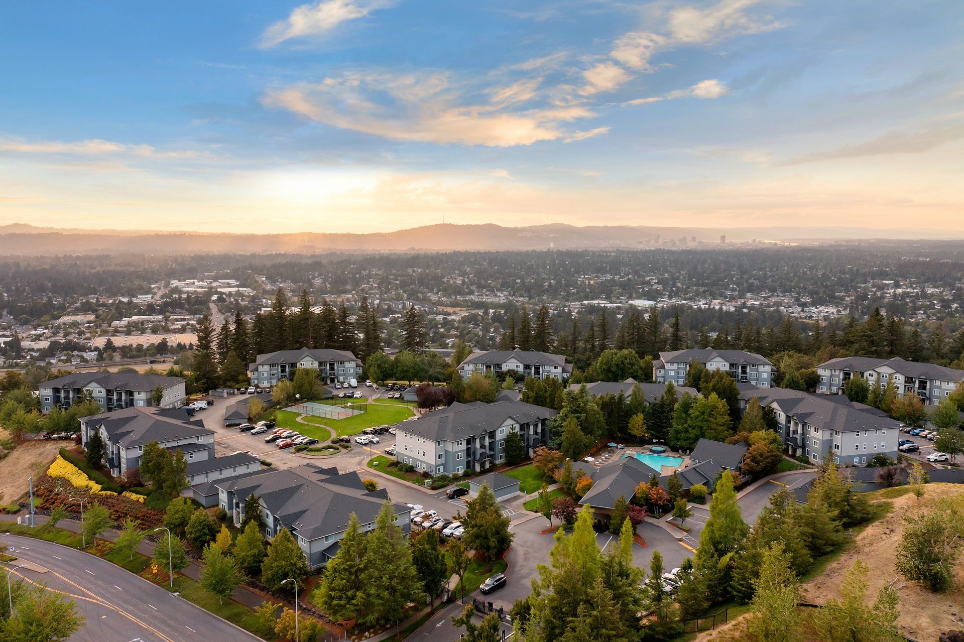 Drone view of an apartment community with buildings and a pool.
