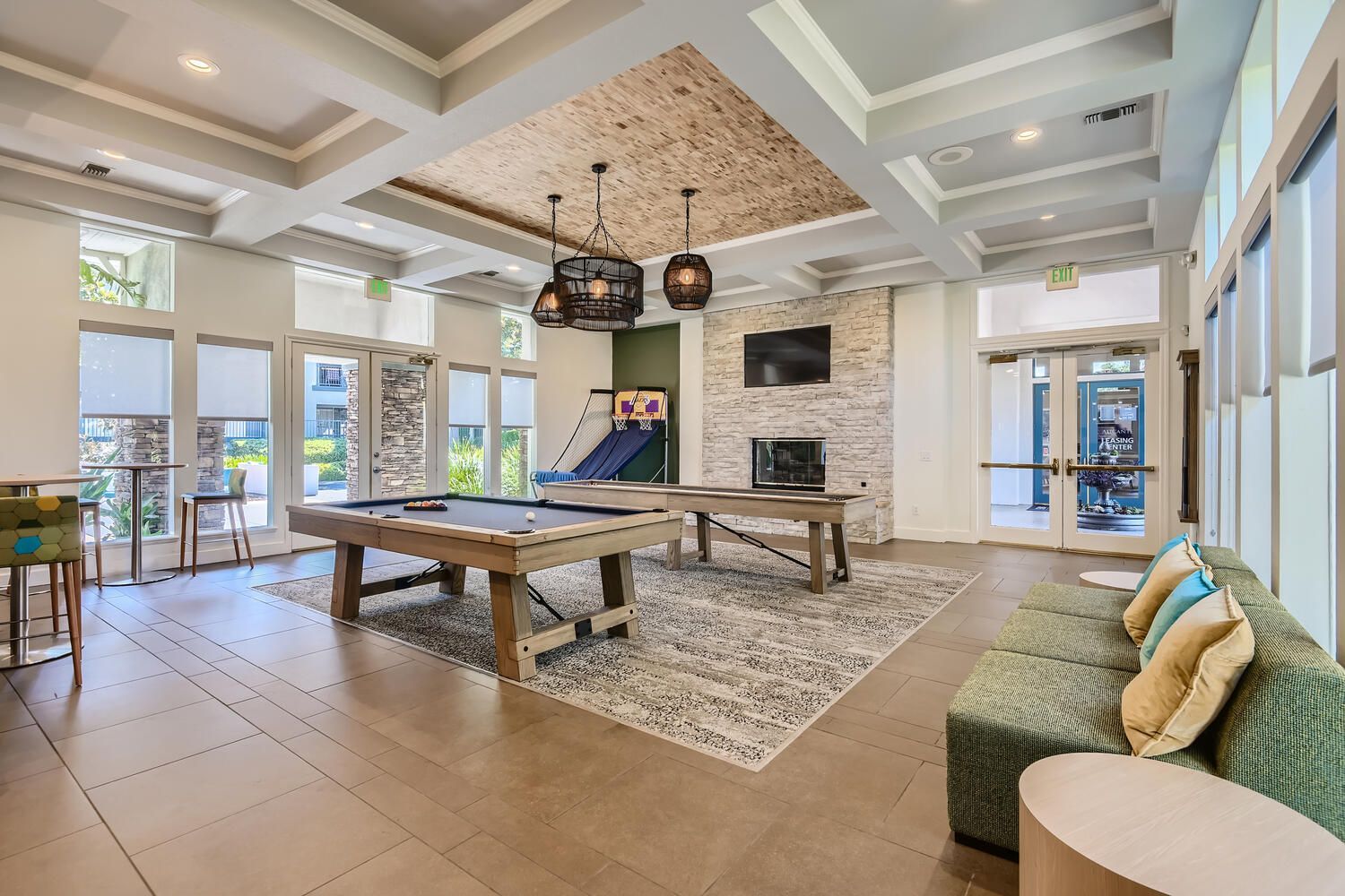 Living room with brown leather sectional, two gray chairs, coffee tables, and mountain art.