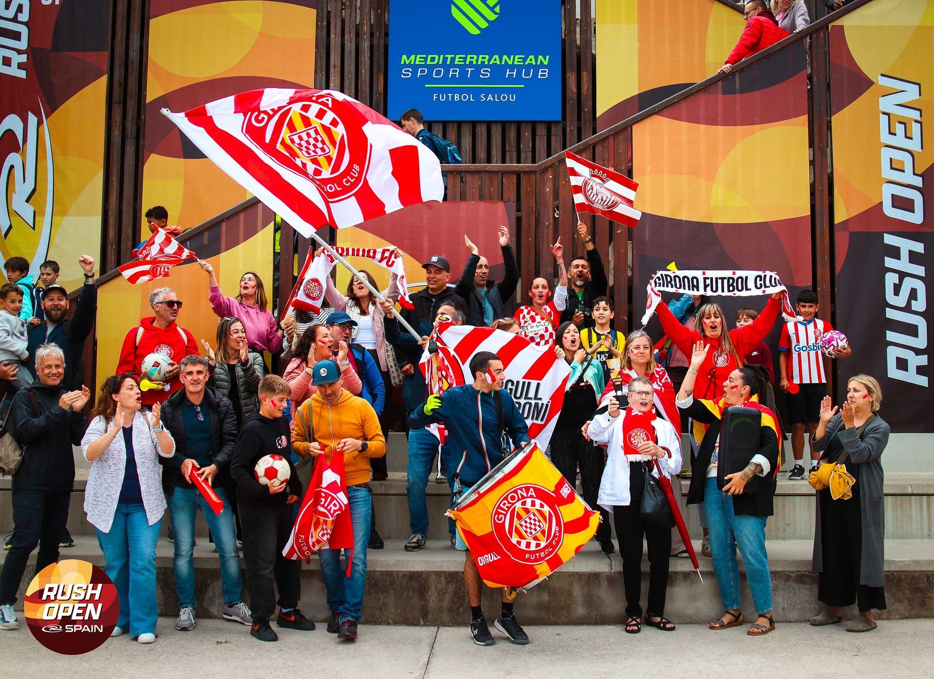 Fans posing with red and white flags outside a sports venue entrance