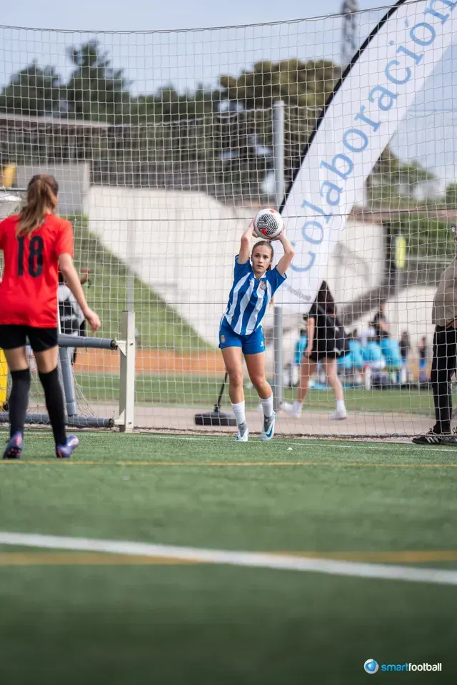 Soccer player in blue throws ball during game on field.