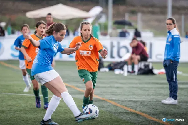 Soccer players in blue and orange jerseys on a green field, competing for the ball.