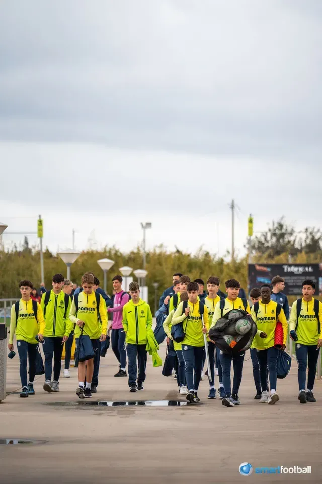 Soccer team in yellow jackets walking together outdoors under overcast sky.
