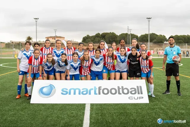 Female soccer team poses with a referee in front of a 
