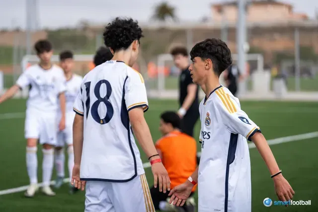 Two young soccer players in white jerseys with the number 18, facing each other on a green field.