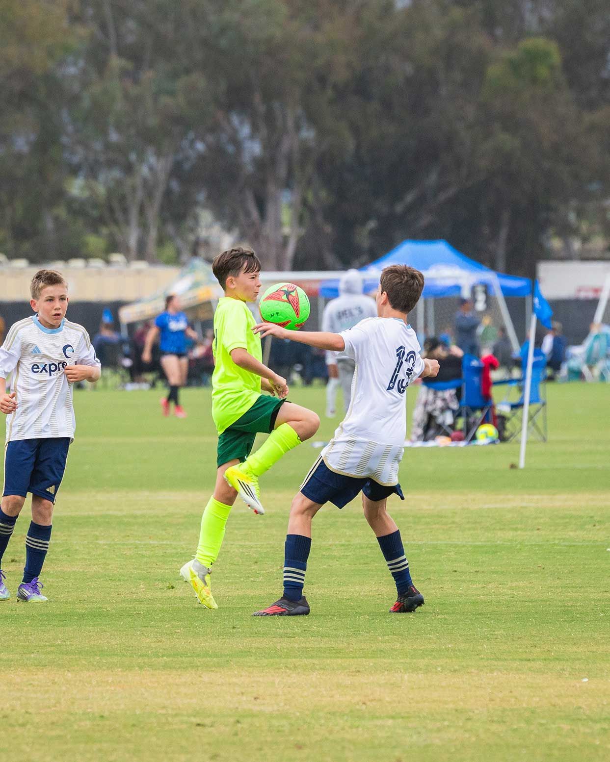 Youth soccer players contesting a high ball on a grassy field during a match
