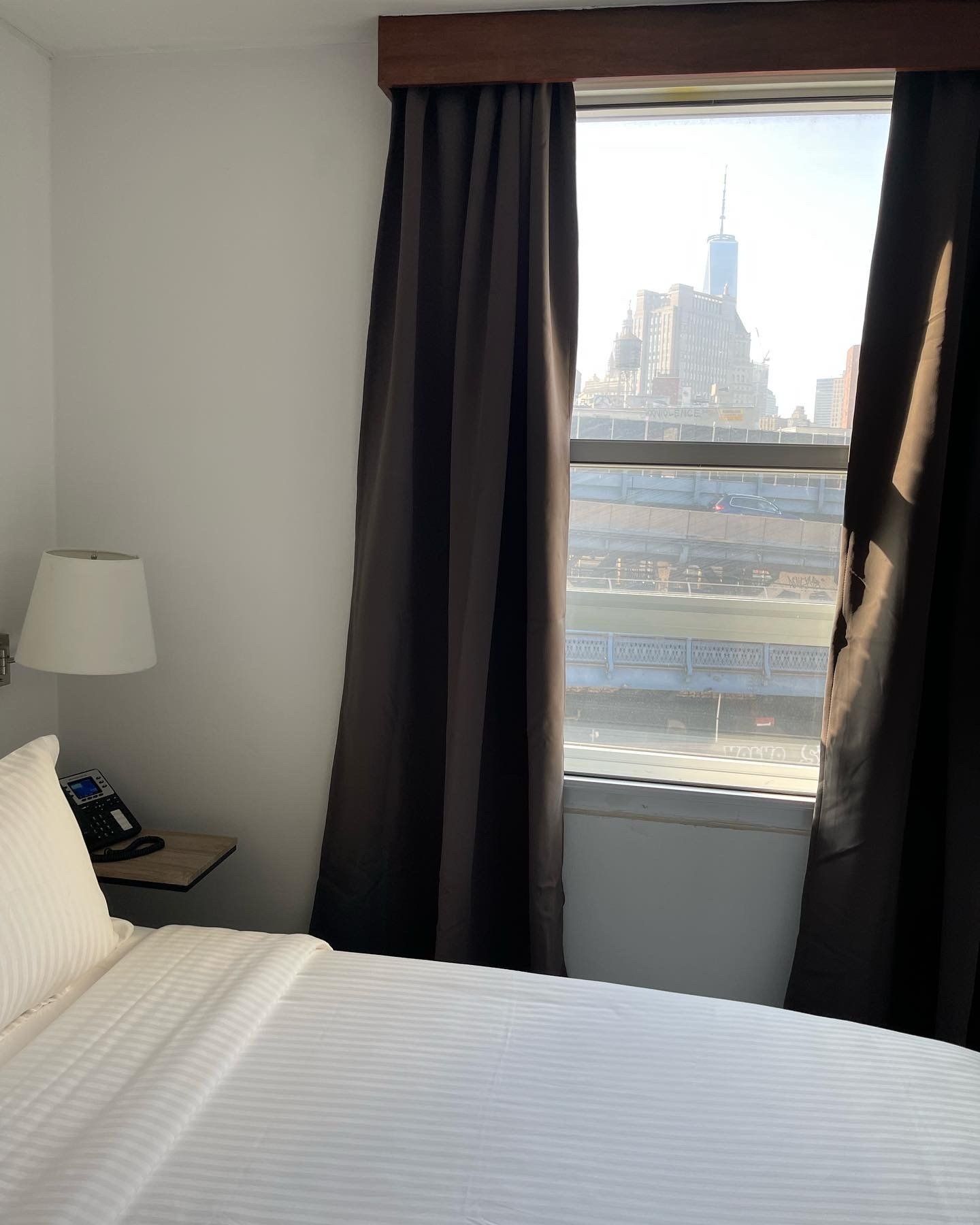A hotel room with a bed a lamp and a window